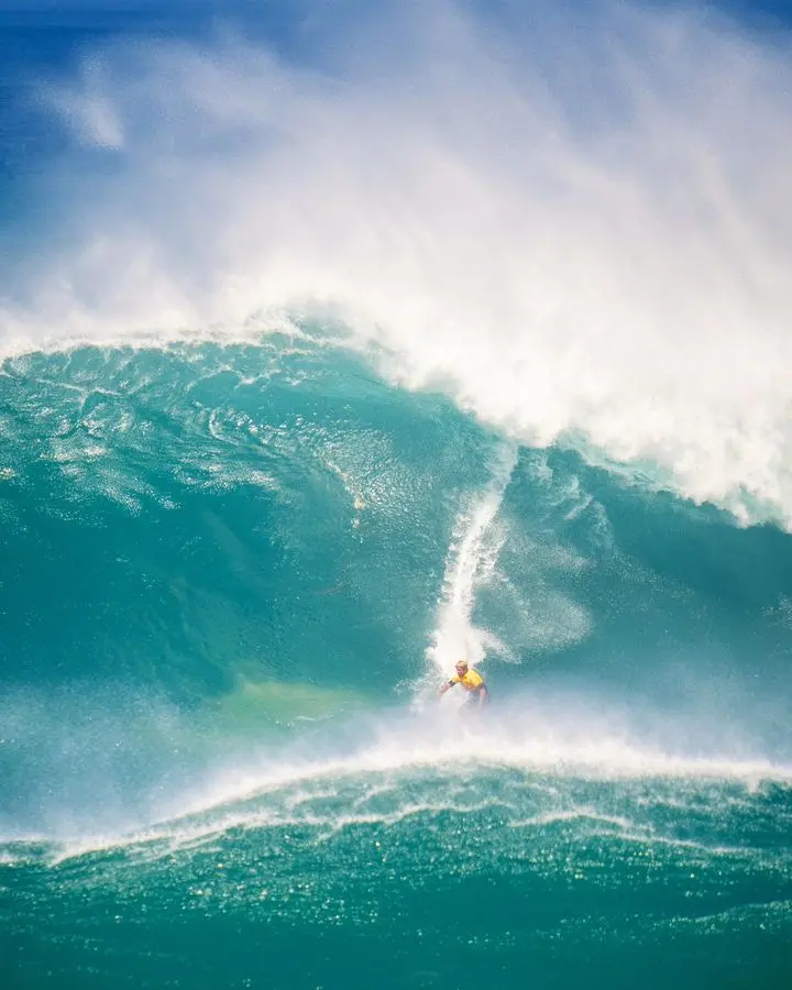 Surfer expertly riding a huge wave, showcasing adventure and skill in a vibrant ocean scene.