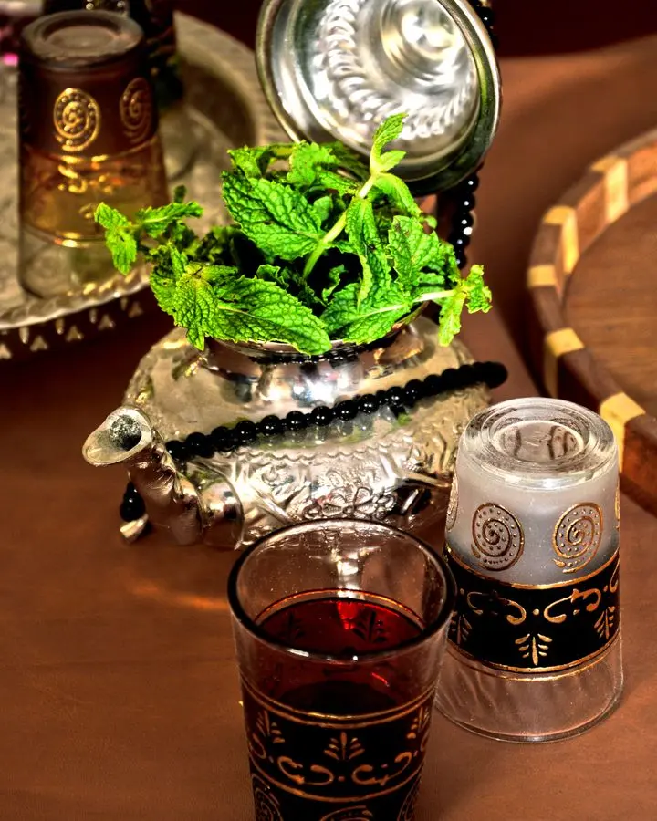 Elegant arrangement of traditional Moroccan mint tea with ornate glasses and teapot.