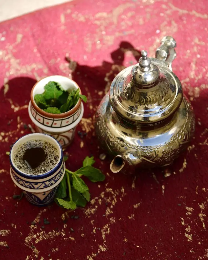 Authentic Moroccan mint tea set with silver teapot and cups on a vibrant red rug, Fès, Morocco.