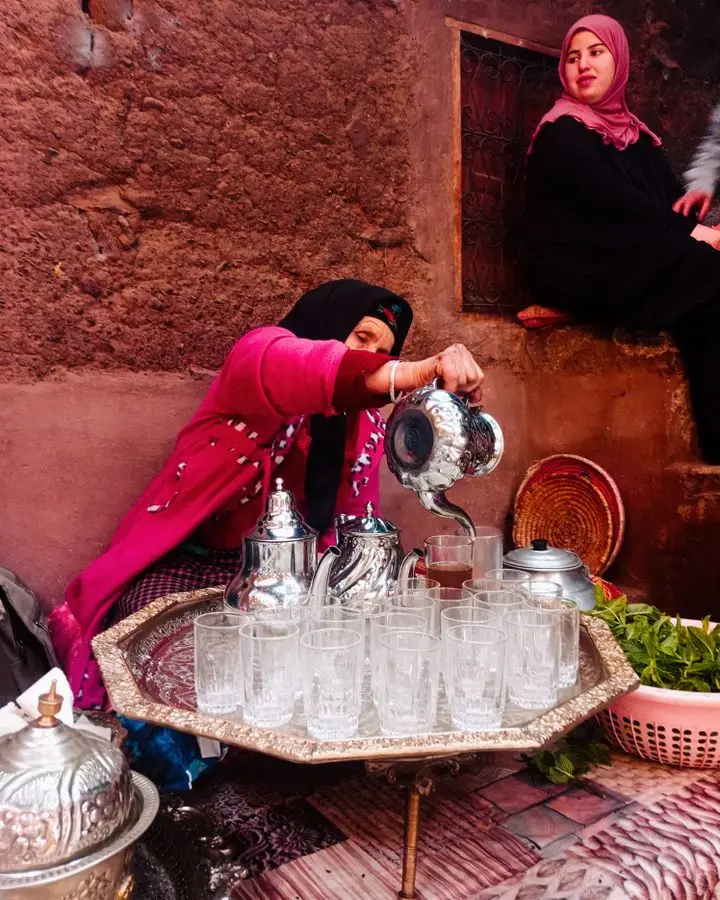 Woman pouring Moroccan mint tea at a traditional market. Authentic cultural scene.