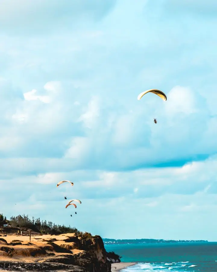 Exciting paragliding over cliffs at Pipa Beach, Brazil, with stunning ocean views.