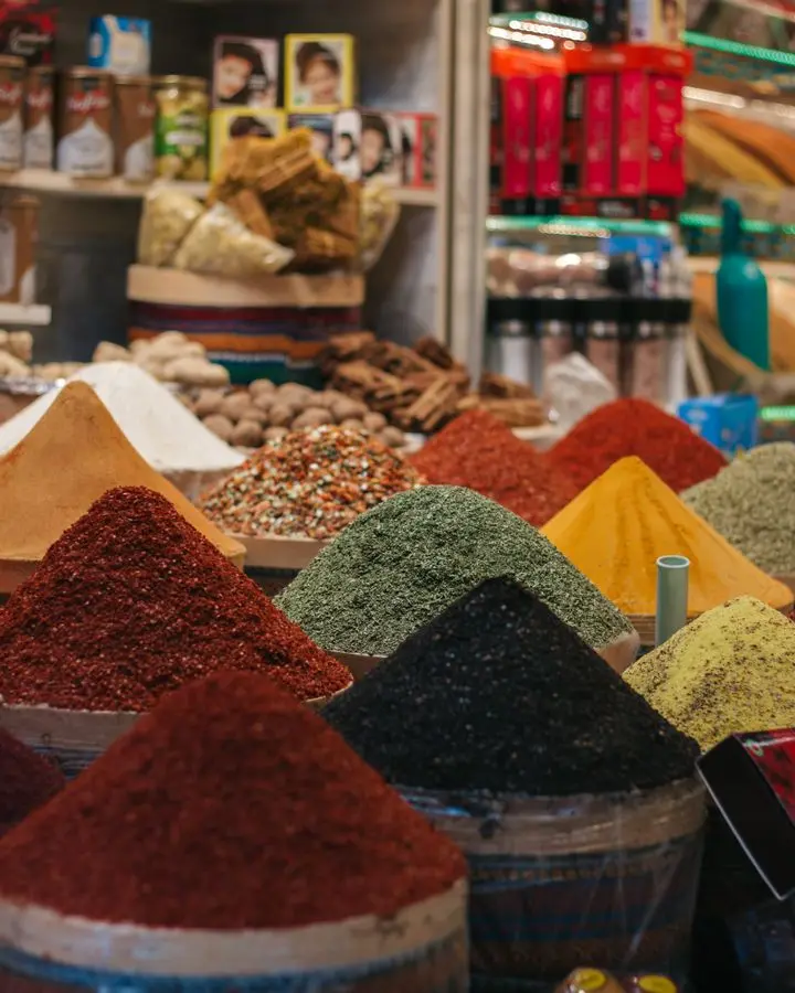 Colorful variety of spices in a bustling market setting, featuring vibrant powders and aromatic herbs.